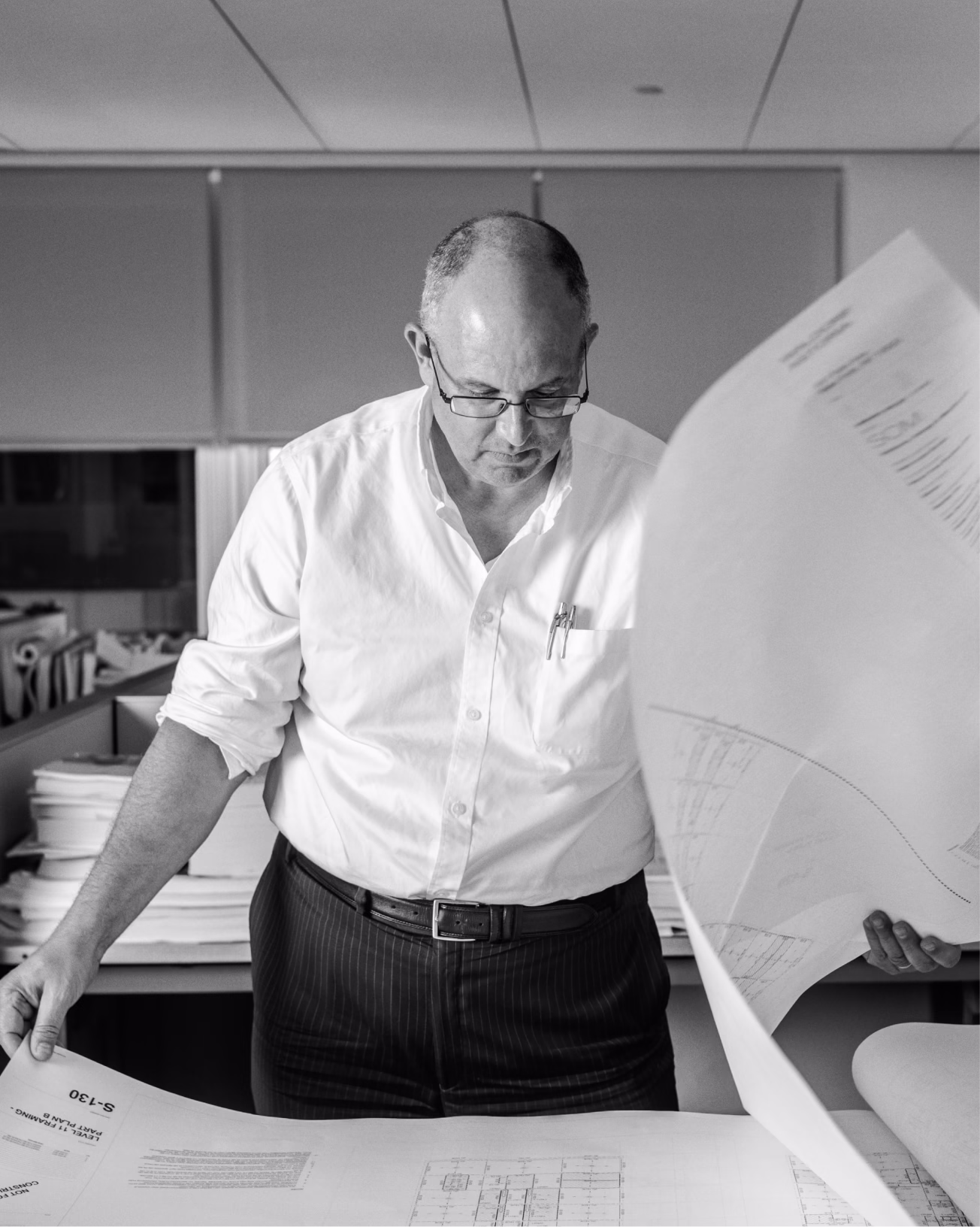 Executive over blueprints, editorial portrait
